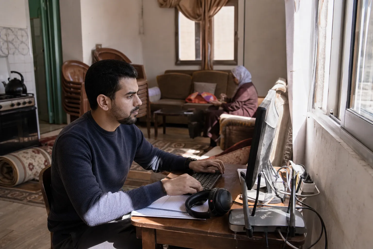 موظف عربي يعمل عن بُعد أمام حاسوب في المنزل