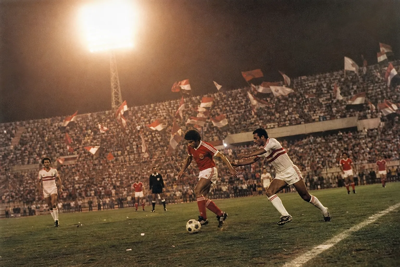 ملعب مصري مكتظ بالجماهير في الثمانينيات خلال مباراة قمة بين الأهلي والزمالك، عصر نجوم الكورة المصرية.
